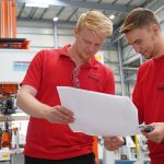 Two trainees looking at the assembly plan of the Multi Panel Assembly Cell (MPAC).